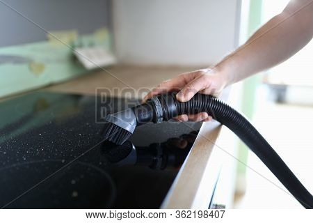 Close-up Of Persons Hand Cleaning Cookstove Display With Nozzle Of Vacuum Cleaner. Male In Protectiv