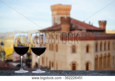 Two Glasses Of Barolo Wine On A Windowsill With The Castle Of Barolo (piedmont, Italy) Blurred On Th