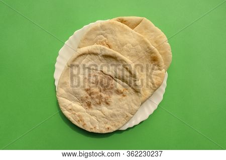 Famous Traditional Arabic Pita Bread In White Plate On Green Background. Flat Lay, Top View. Indian 