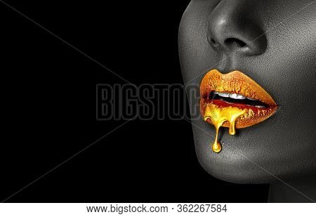 Gold Paint smudges drips from African American woman face, lips lipgloss dripping from sexy lips, golden liquid drops on beautiful model girl's mouth, make-up. Beauty woman makeup close up. 