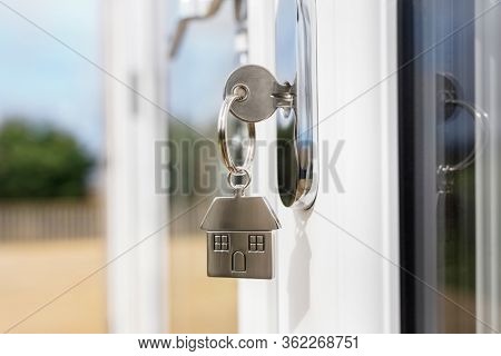 House key on a house shaped chrome keyring in the lock of a outside door