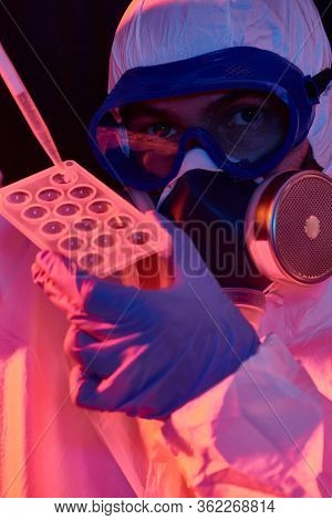 COVID-19 or 2019-nCoV. Close-up portrait of a scientist microbiologist in a protective PPE suit making a research on blood samples of infected people.