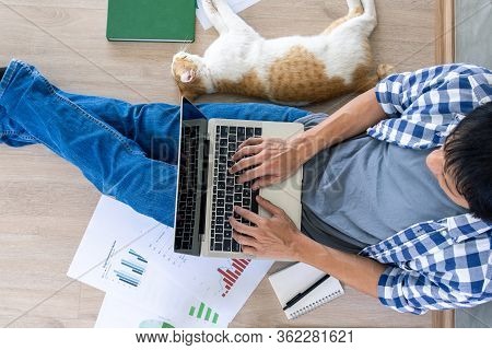 Man Sit On The Floor In The House With A Pet. Working At Home With Documents Sheets Printed In Noteb