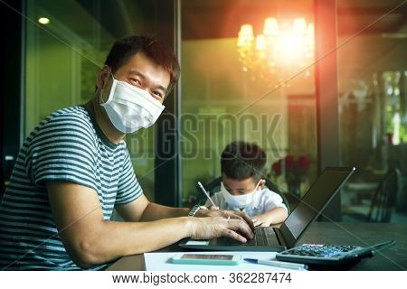 Quarantine Asian Man And Children Wearing Protection Mask Working On Computer At Home While Covid-19