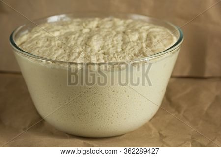 Glass Bowl With Aired Yeast Raised Dough On Paper Background