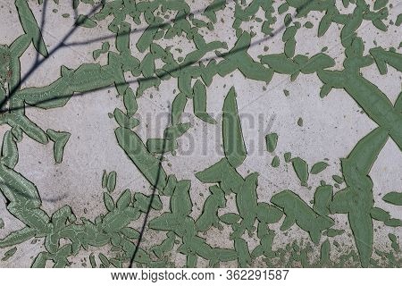 Green Peeled Off Painting On A White Base Outdoors. Twigs In The Foreground. Puste Ulany, Slovakia.