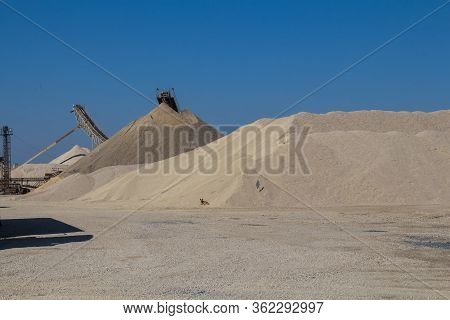 Hills Of Gravel At A Minining Plant. Dog At A Bottom Of The Pile. Parts Of Machinery. Bright Blue Sk