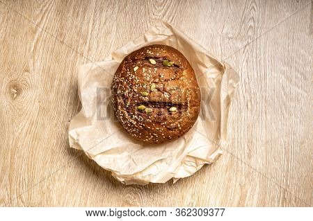 Tasty Fresh Baked Loaf Of Dark Bread With Sesame Seeds On Light Background With Paper Cower