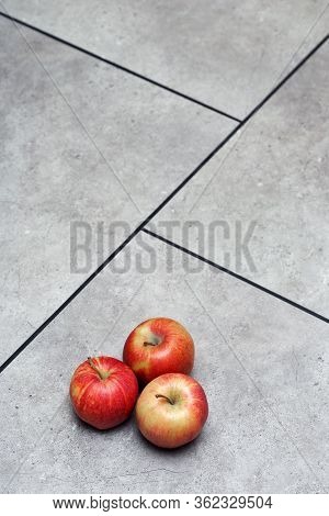 Red Apples, On Grey Floor Tiles With Black Seams