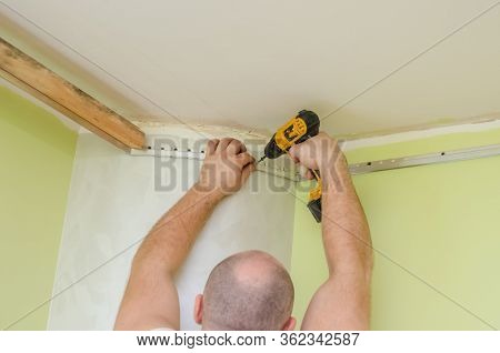 Fastening To The Wall Guide For Stretch Ceiling. Repairers Make Installation Of A Stretch Ceiling