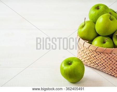 Apples Harvest Concept. Braided Bamboo Basket With Green Apples On White Wooden Background With Copy