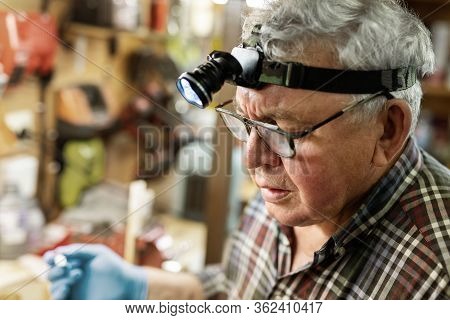 Senior Craftsman Portrait With Headlamp Led Torch Working In Workhop With Tools And Equipment On Bac