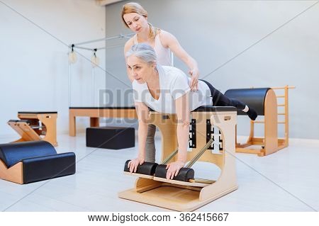 Woman Woman Doing Pilates On The Pilates Cadillac, Supporting And Helping Her Positive Young Woman I