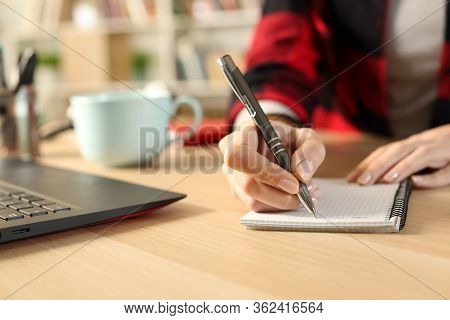 Close Up Of Student Girl Hands Taking Notes On Notebook On A Desk At Home