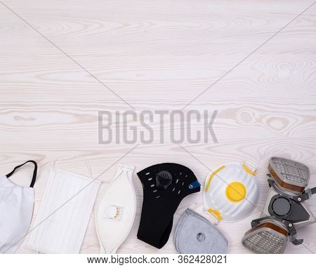 Different protective masks on wooden background, top view with copy space