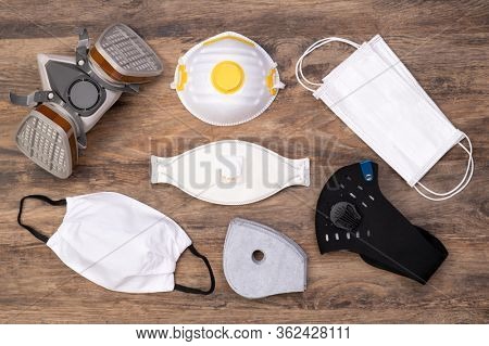 Different protective masks on wooden background, top view
