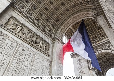 View Of Arc De Triomp With Flag Of France Waving In Wind On Place De Gaulle In Paris, France