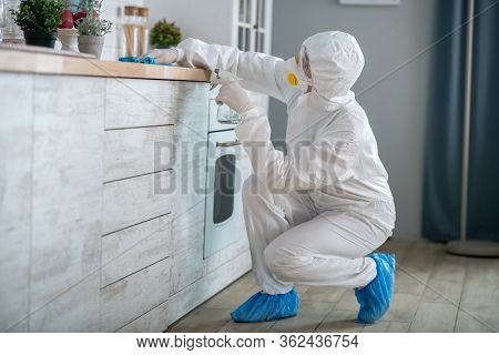 Woman In White Workwear And Protective Gloves Cleaning The Surface