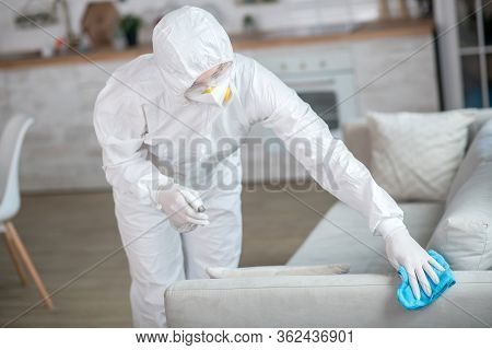 Woman In White Workwear And Protective Gloves Disinfecting Furniture
