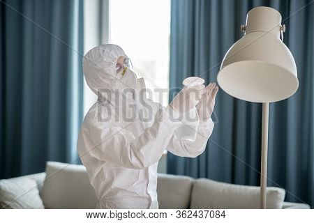 Woman In White Workwear And Protective Eyeglasses Disinfecting The Lamp