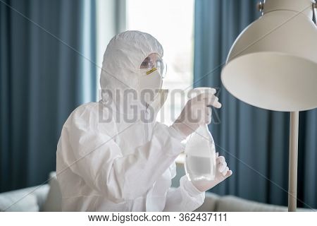 Woman In White Workwear And Protective Eyeglasses Cleaning The Lamp