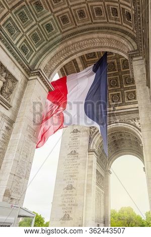 View Of Arc De Triomp With Flag Of France Waving In Wind On Place De Gaulle In Paris, France