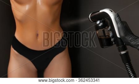 Cosmetology Professional Applying Liquid Tan Spray On Woman Skin With Aerograph On Black Background