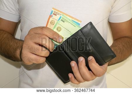 Kazakhstan National Currency. Kz Money Banknotes. Man In White T Shirt Put Tenge Banknotes Into Blac