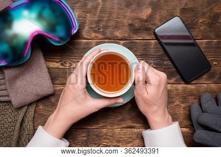 Woman A Snowboarder Is Drinking Hot Black Tea From A Cup.