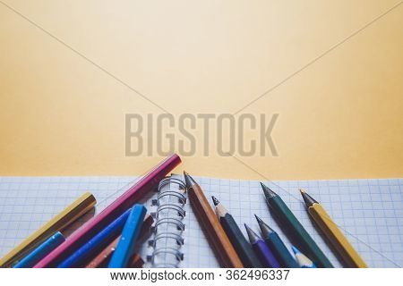 School Supplies On Yellow. Bright Back To School Background. Notepad And Stack Of Colorful Pencils. 