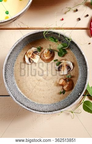Forester soup with cheese rusks in gray bowl. Liquid dish, first course with greenery and mushrooms decoration close up. Served creamy broth, puree, mashed soup. Hot restaurant meal
