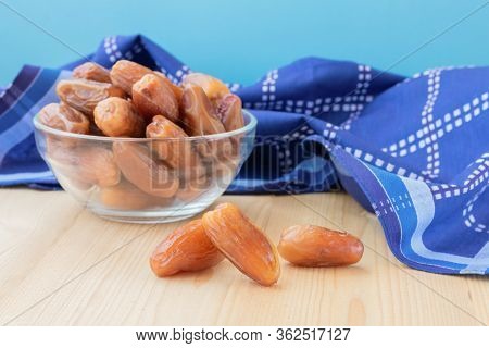 Pile Of Dried Sweet Deglet Nour Date Fruites In Translucent Bowl And Dark Blue Napkin.organic Vegeta