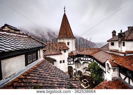 Bran Castle roofs on misty mountains background