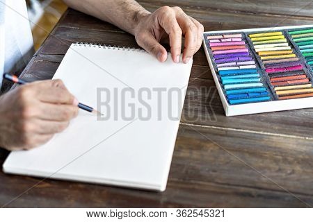 Person, Artist Painting With A Pastel Crayon Chalk On A White Sheet Of Paper.box With Pastel Chalks