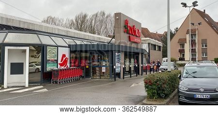 Paris, France - Mar 21, 2020: French Auchan Supermarket In Robertsau With People Queue Keeping Dista