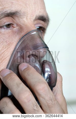 A Man Breathes Oxygen Using A Mask. Close-up Of An Old Man Doing Inhalation
