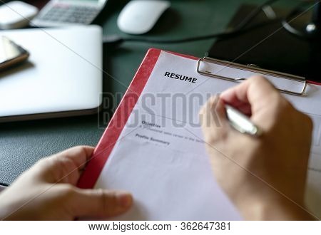 Closeup View Of Hiring Manager Reviewing Resume At His Office Desk