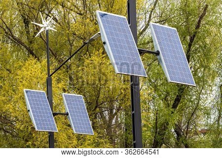 Street Electricity By Small Windmill And Solapanels In The City Against Buildings In Daytime. Concep