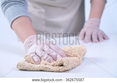 Young Woman Housewife Is Cleaning, Wiping Down Home Table Surface To Stop The Spread Of Infection Wi