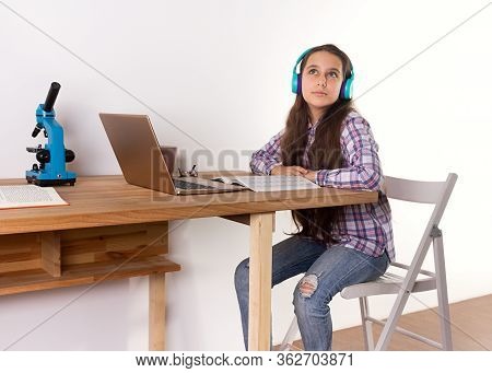 Distance Learning.home Schooling, Young Teen Girl Studying At A Laptop, Listening To Music With Head