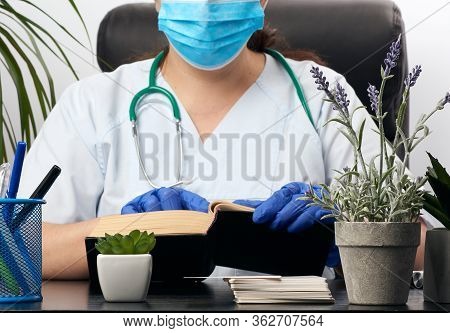 Medic In A Blue Uniform Sits At A Table And Reads A Book