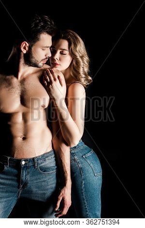 Sensual Girl Embracing Shirtless, Muscular Boyfriend Isolated On Black