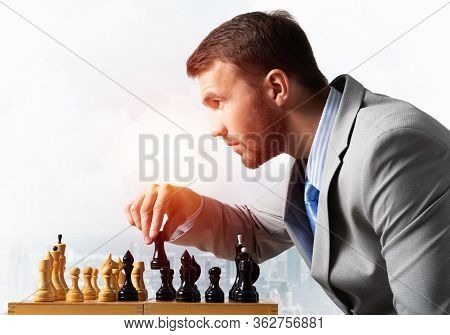 Businessman Moving Chess Figure In Chessboard. Successful Management And Leadership. Handsome Man In