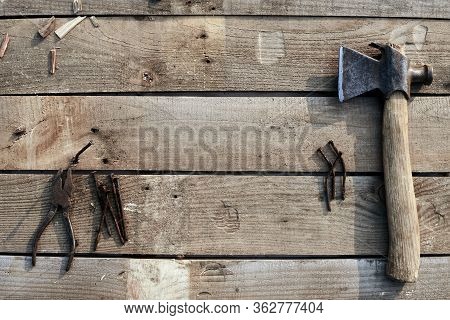 A Hammer, Pliers And Bent Nails Old Lie On A Tree Desktop. Rust. Cracked, Scratched Homemade Table. 