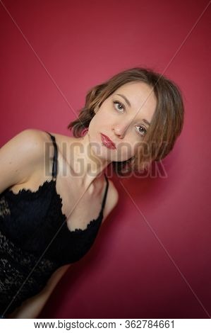 Young Woman With Short Hair Dressed In Black Lace Bustier And Blue Jeans Is Posing In The Studio On 