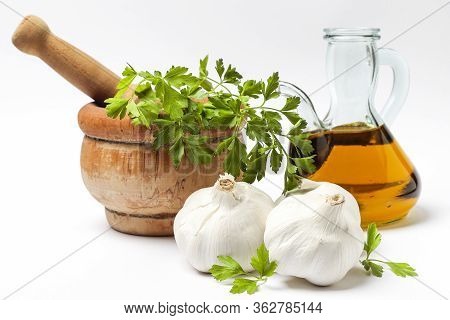 Still Life Of An Oil Pourer With Olive Oil, Three Head Of Garlic And Leaves Of Parsley Isolated On W