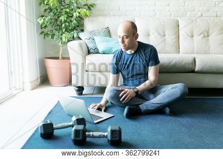 Caucasian Bald Man Looking For Some Online Workouts On A Laptop Computer And Getting Ready To Exerci