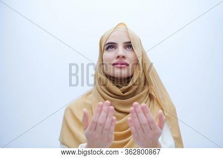 beautiful muslim woman in fashionable dress with hijab making traditional prayer to God, keeps hands in praying gesture isolated on white background representing modern islam fashion and ramadan karee