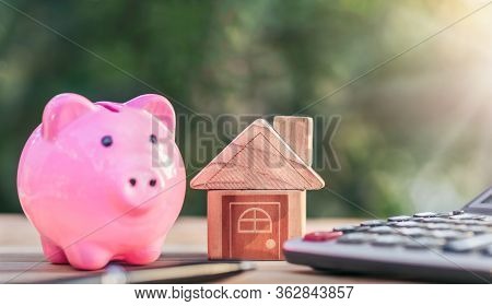 House Placed On Table. Pen And A Piggy Bank On The Table. Planning Savings Money Of Coins To Buy A H