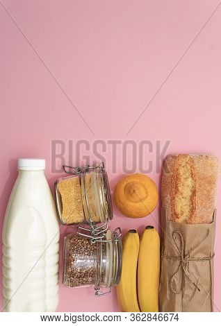 Donation Food. Corn, Buckwheat In Jar, Bananas, Milk, Bread, Bananas On Pink Background.
